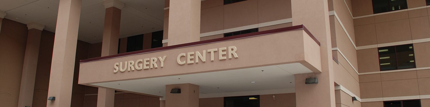 Image of the entrance to the Central Kentucky Surgery Center, a modern building with glass windows, doors, and a sign that reads "Central Kentucky Surgery Center" in blue.