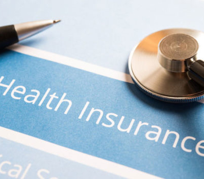 An image of a person holding an insurance card with the words "Health Insurance" in blue.