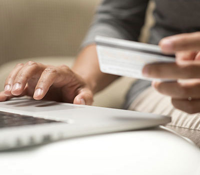 An image of a person paying a bill online with a computer and a credit card.