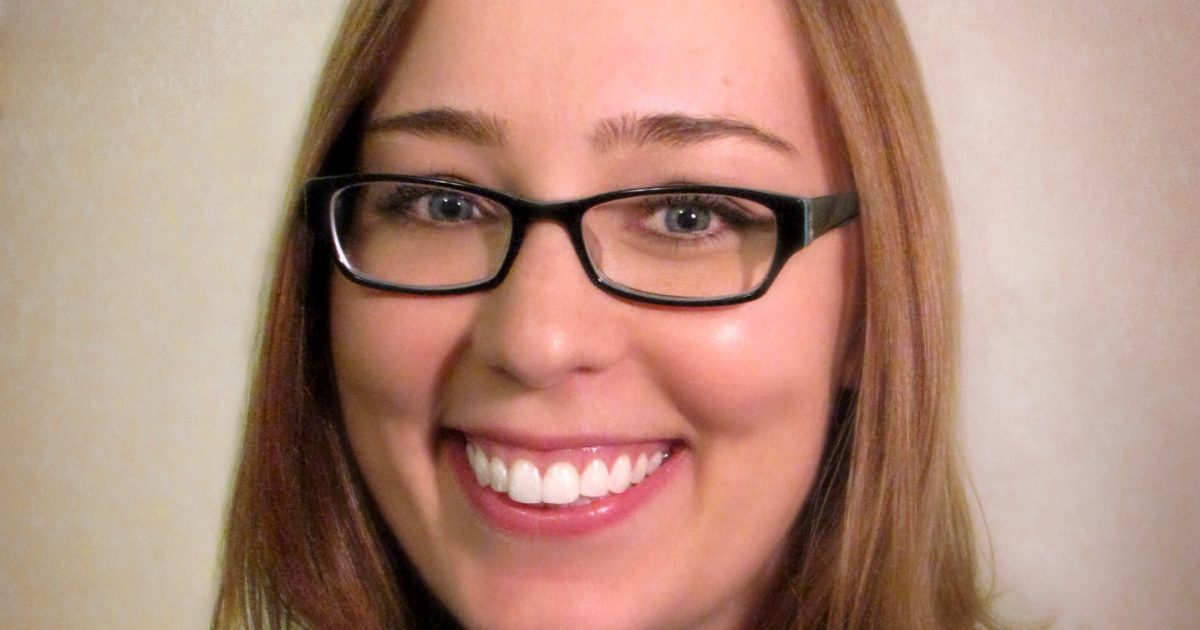 a woman wearing glasses and smiling at the camera