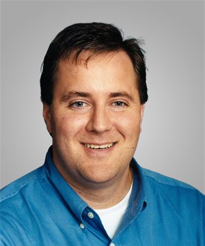 a man wearing a blue shirt and smiling at the camera